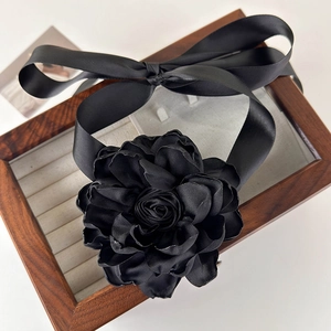Gros plan d'un collier choker fleur noire en tissu avec rubans dans un coffret