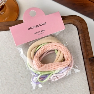 Dettaglio di elastici per capelli color pastello in confezione con cartellino rosa
