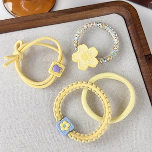 Detailed set of four yellow spring hair ties featuring colorful beads and flower charms