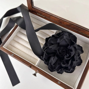Gros plan d'un choker fleur en tissu noir avec longs rubans de satin sur boîte en bois