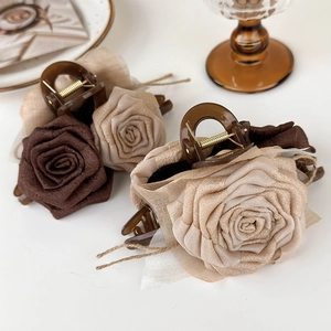 Close-up of elegant fabric rose hair claws with polished resin and gold metal springs