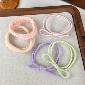 Dettaglio di cinque elastici per capelli colorati con fiocchi su un vassoio di legno