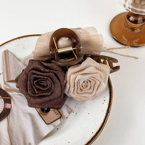 Detail of elegant fabric rose hair claw clip in vintage caramel and cream tones