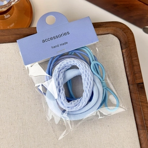Dettaglio degli elastici per capelli blu con fiocco su un vassoio da esposizione in legno