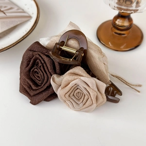 Detail of elegant fabric rose hair claw clips in brown and champagne on a desk