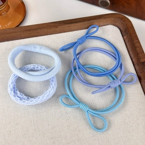 Dettaglio di cinque elastici per capelli sfumati blu con fiocchi su un vassoio di stoffa