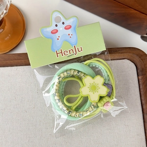 Detail of green floral hair tie set with plush scrunchie and beaded flower elastic bands