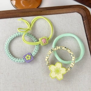 Close-up of four floral hair ties with beads and fabric textures in a wooden tray