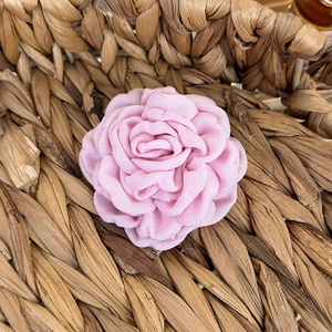 Close-up of pink fabric rose hair claw in a woven basket with a rustic garden aesthetic