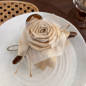 Detailed view of a champagne rose hair claw clip with linen rope on a ceramic plate