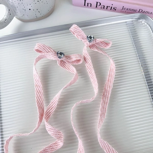 Detail of pink satin bow hair clips with heart-shaped crystal on a silver tray