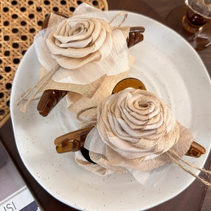 Detailed set of two retro beige fabric rose hair claws on a ceramic plate display