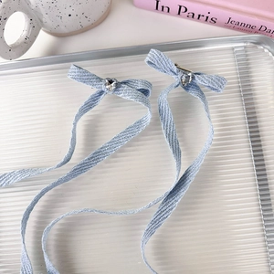 Detail of light blue denim bow hair clips with heart crystal and long flowing ribbons