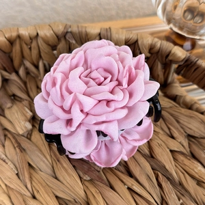 Detail of pink fabric rose hair claw clip with multi-layer petals in a woven basket