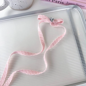 Detailed view of a pink bow hair clip with a heart-shaped crystal on a glass tray
