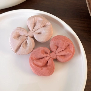 Vue détaillée de barrettes à nœuds en satin mat aux couleurs champagne et rose corail