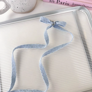 Detail of light blue woven ribbon bow hair clip with heart rhinestone and long streamers