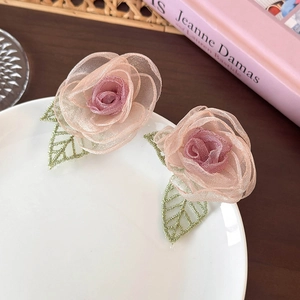 Vue détaillée des boucles d'oreilles rose en tulle avec des feuilles brodées vertes