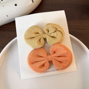 Détail de barrettes à nœuds en ruban fait main aux couleurs jaune vif et orange corail