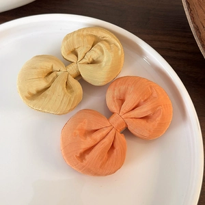 Gros plan de barrettes à nœuds en tissu jaune et orange sur une assiette blanche