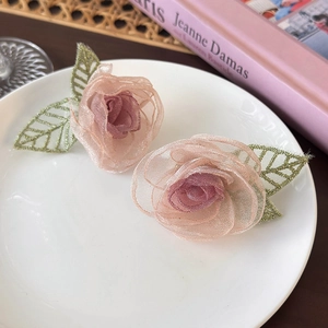 Détail de boucles d'oreilles roses en tulle avec feuilles en organza sur un plateau