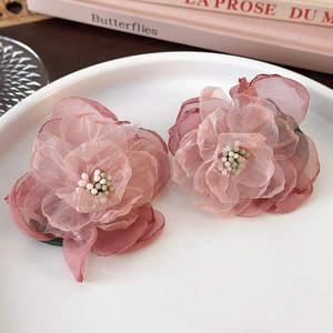 Detailed view of two pink organza floral hair clips with layered petals on a ceramic plate