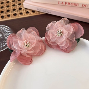 Detailed macro of handmade 3D pink gradient mesh flower earrings on a white plate