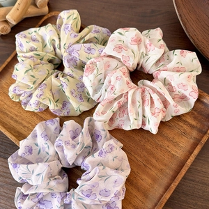 Set of 3 floral chiffon scrunchies in pastel colors on a natural wooden background