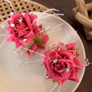 Detail of pink rose hair claw clips with heart rhinestones and delicate white feathers