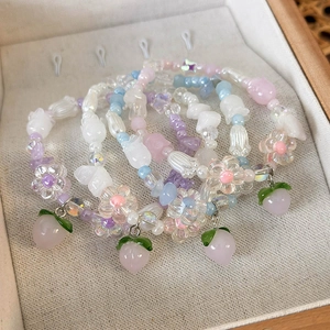 Détail de quatre bracelets de perles faits main avec breloques pêche et fleurs