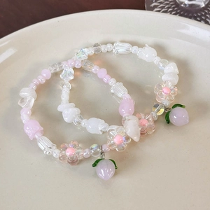 Détail de pendentifs pêche et perles fleurs sur bracelets faits main dans un plat céramique