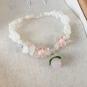Détail d'un bracelet en perles avec breloque pêche rose et tulipes blanches