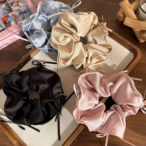 Dettaglio di quattro elastici in raso con nastri in nero, blu, oro e rosa