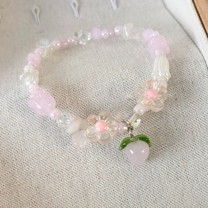 Gros plan d'un bracelet en perles roses et blanches avec pendentif pêche et tulipes