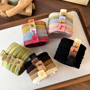 Detail showing plush elastic hair ties with marine labels and decorative charms