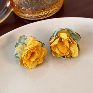Detail of yellow mesh flower earrings with green leaf petals on a vintage dish