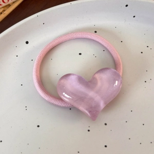 Gros plan sur élastique rose avec pendentif coeur translucide sur assiette blanche