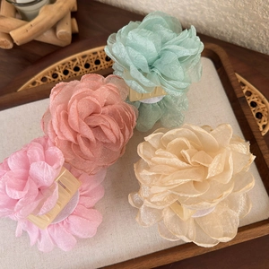 Détail de quatre pinces à cheveux en fleurs d'organza colorées sur un plateau