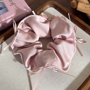 Dettaglio di un elastico in raso rosa con eleganti fiocchi su un vassoio