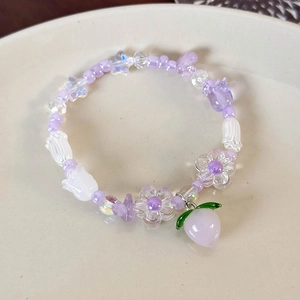 Détail d'un bracelet en perles avec tulipes mauves et pendentif pêche sur plateau