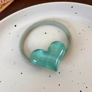 Détail de l'élastique à cheveux cœur vert menthe sur plateau en céramique poli