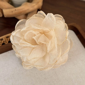 Détail de la pince à cheveux fleur en organza champagne avec des pétales multicouches