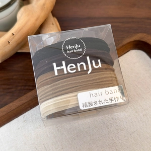 Macro shot of five earth-toned high-elastic hair bands in a clear square packaging box