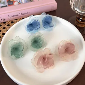 Delicate organza floral earrings in pastel blue, green, and pink on a white tray