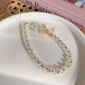 Vue détaillée de la chaîne de téléphone en cristal avec pendentif papillon doré en plateau