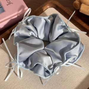 Dettaglio dell'elastico in raso azzurro con piccoli fiocchi in nastro bianco delicati