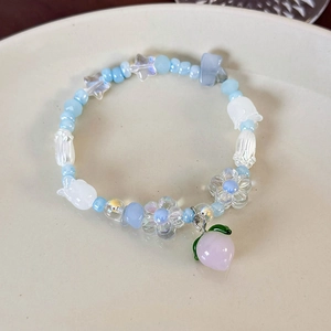 Détail d'un bracelet de perles fait main avec breloque pêche et fleurs bleues
