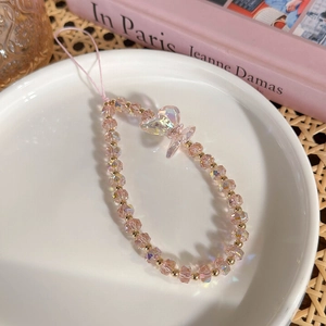 Gros plan d'une lanière de téléphone perlée rose irisée avec pendentif papillon élégant