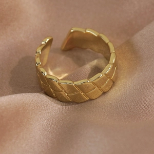 Macro detail of golden open ring featuring textured wheat-ear pattern on silk fabric