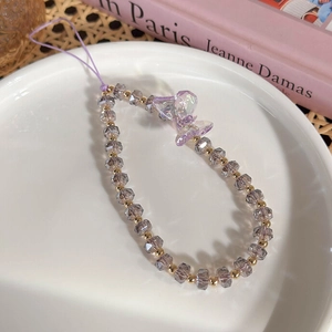 Gros plan d'une dragonne de téléphone en perles violettes avec un charme papillon